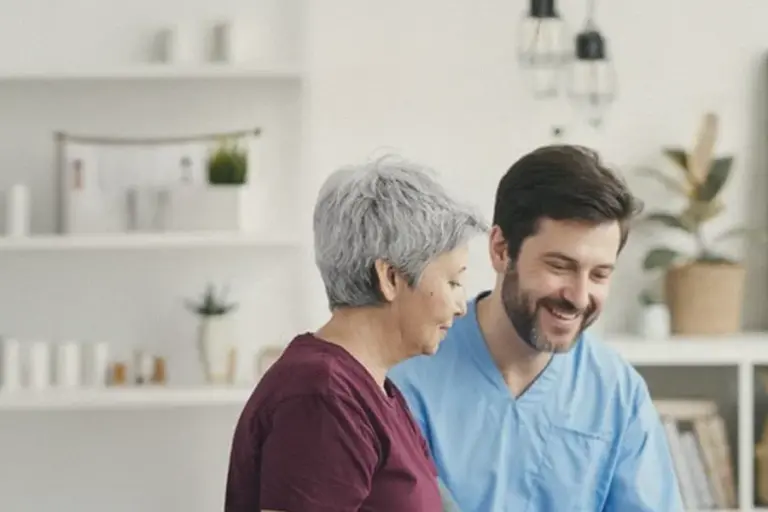 A nurse talks with an older woman in her living room