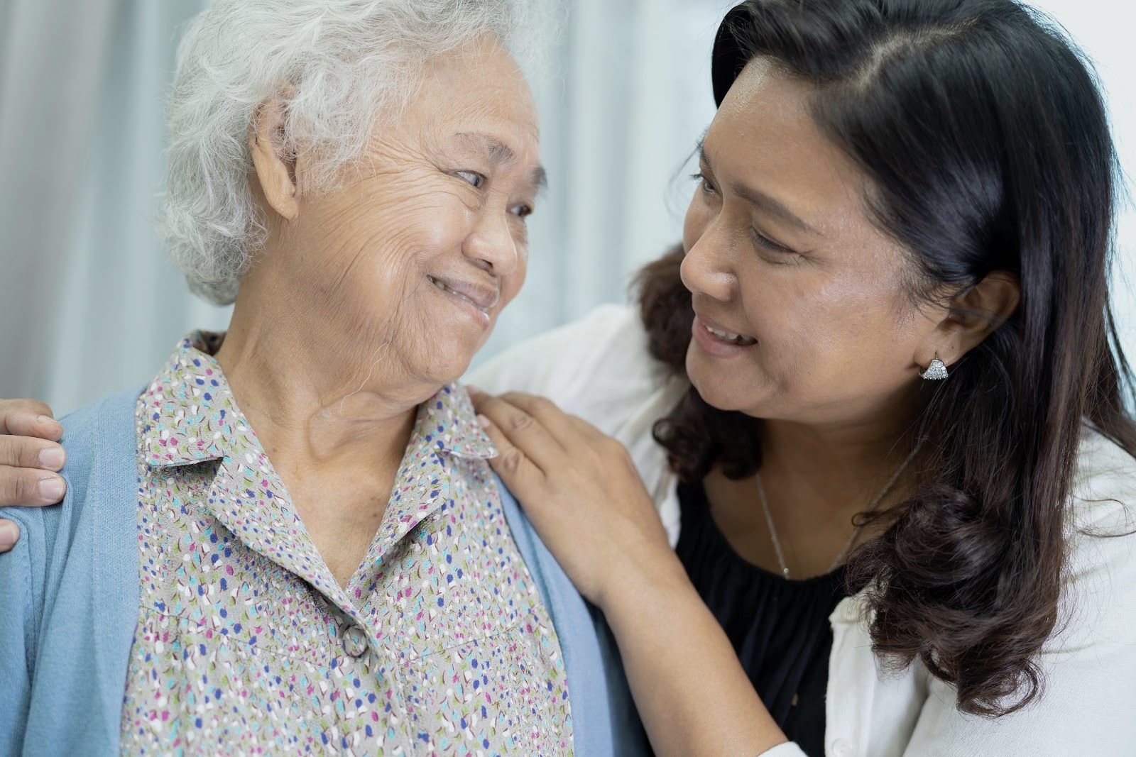 A caregiver and an older woman smile together