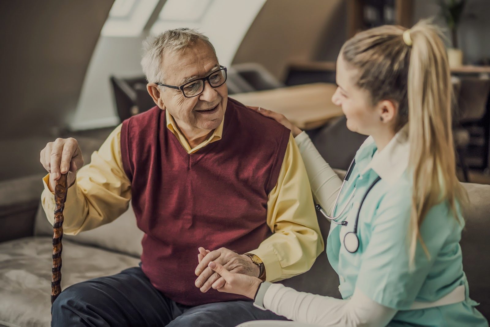 A nurse talks with an older man in his living room